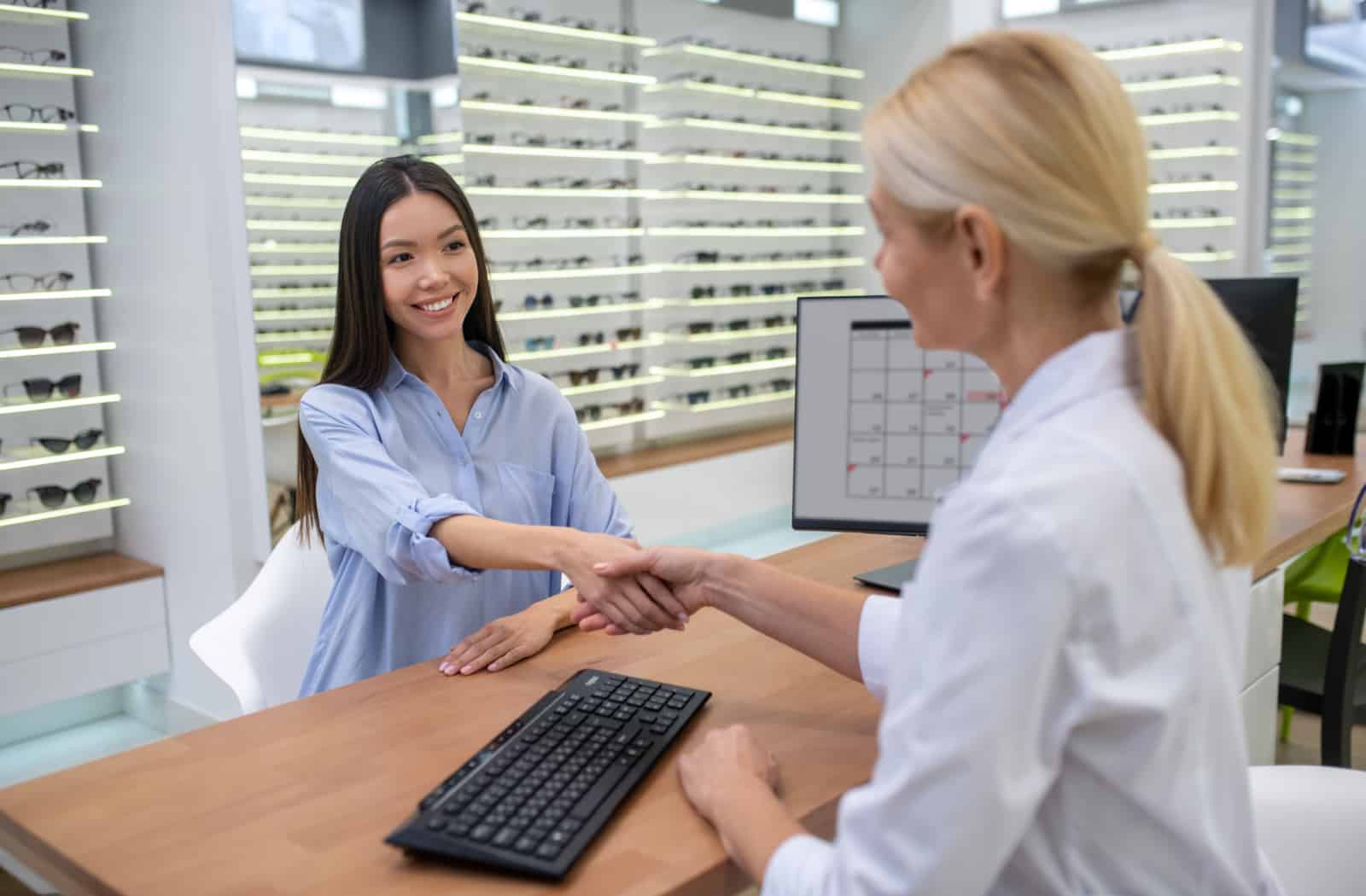 Women shaking hands with female optometrist.