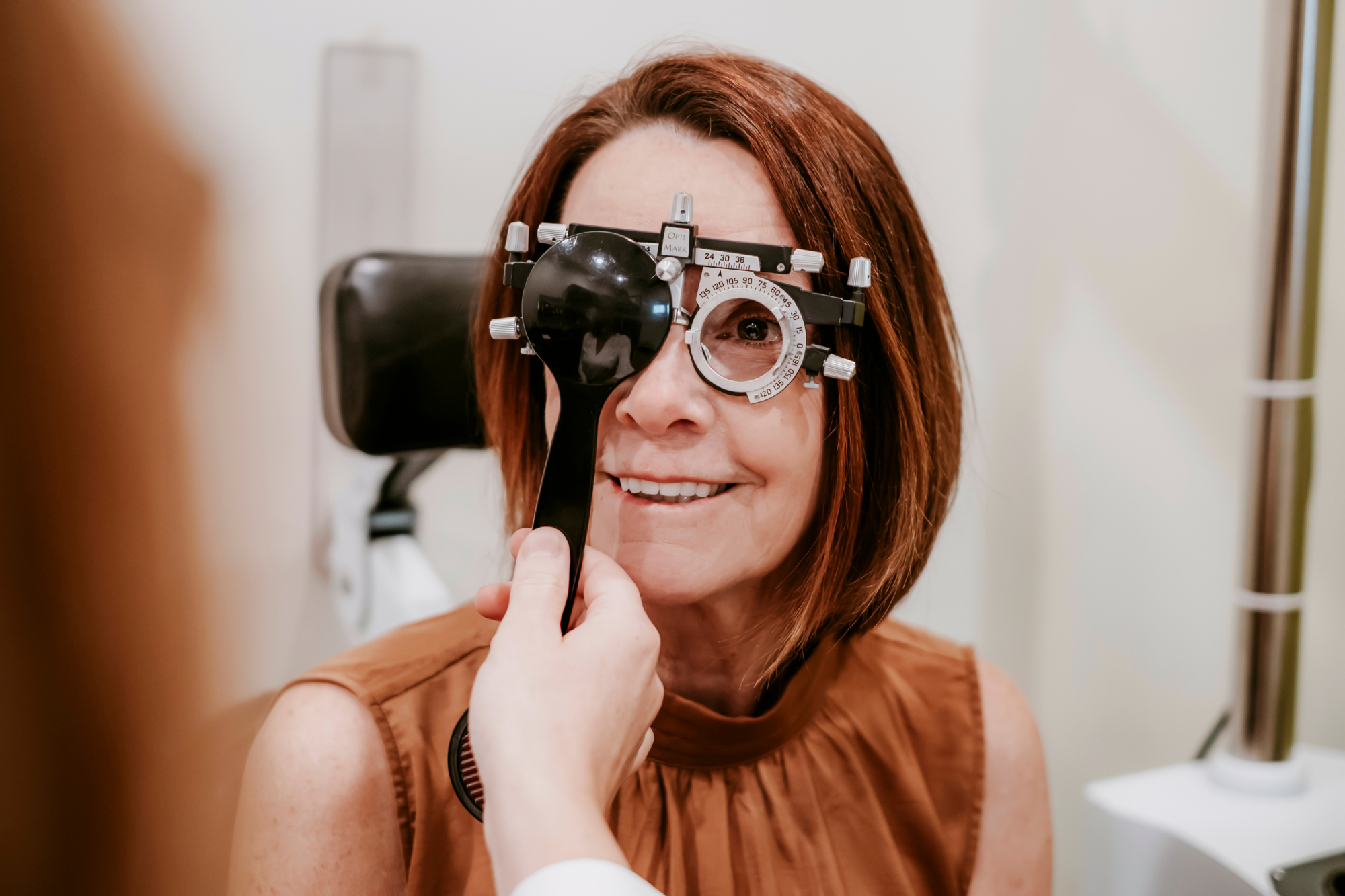 Patient looking through a phoropter while an optometrist evaluates vision and checks for conditions such as glaucoma.